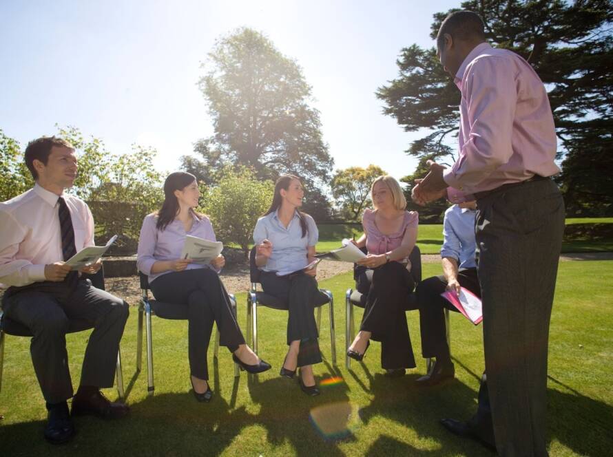Businesspeople sit outside and discuss a client during a corporate event.