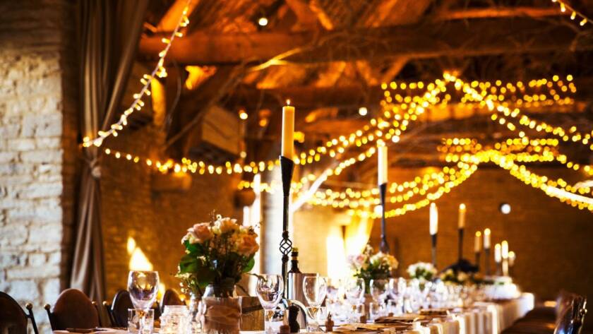 A wedding venue decorated for the reception with fairy lights and the table set for dinner.