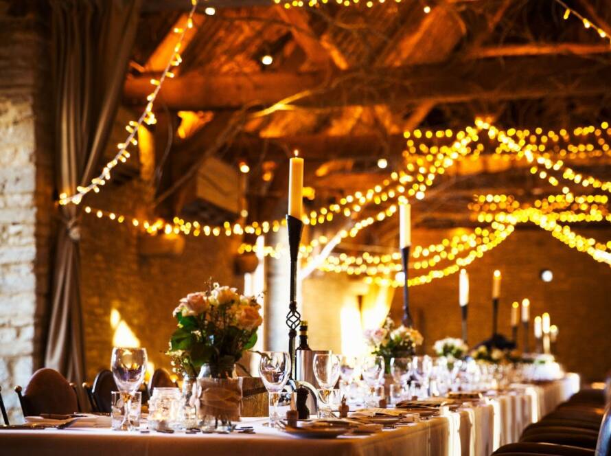 A wedding venue decorated for the reception with fairy lights and the table set for dinner.