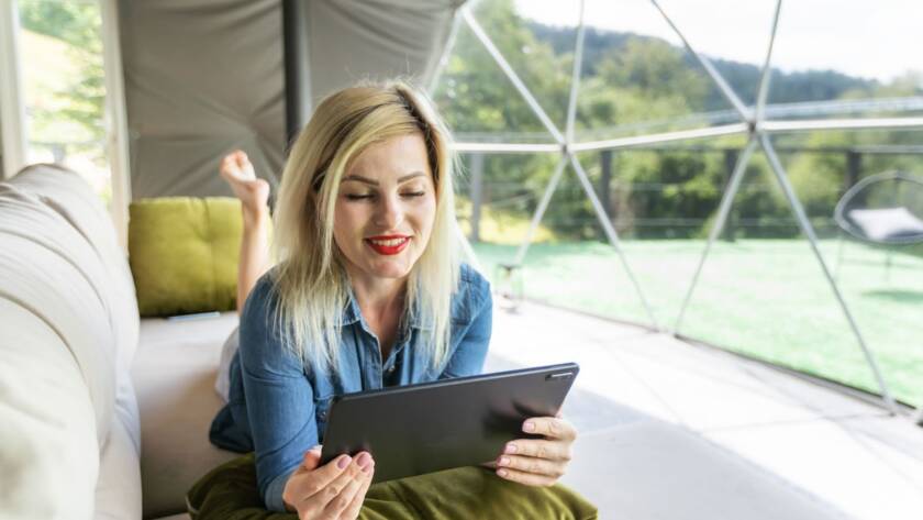 Woman relaxing with a tablet inside a modern dome tent on a glamping vacation