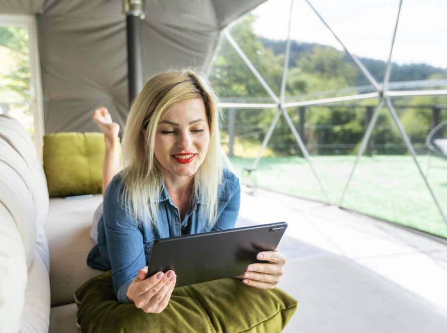Woman relaxing with a tablet inside a modern dome tent on a glamping vacation