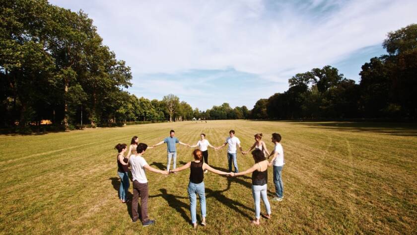 Colleagues gather in a circle amid a scenic natural landscape during a corporate retreat, engaging in team-building and open discussion.