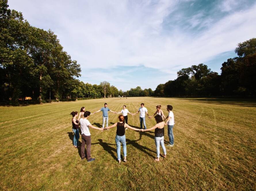 Colleagues gather in a circle amid a scenic natural landscape during a corporate retreat, engaging in team-building and open discussion.