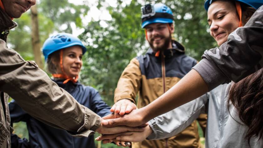 Employees stack their hands together before starting a team-building retreat at the ranch