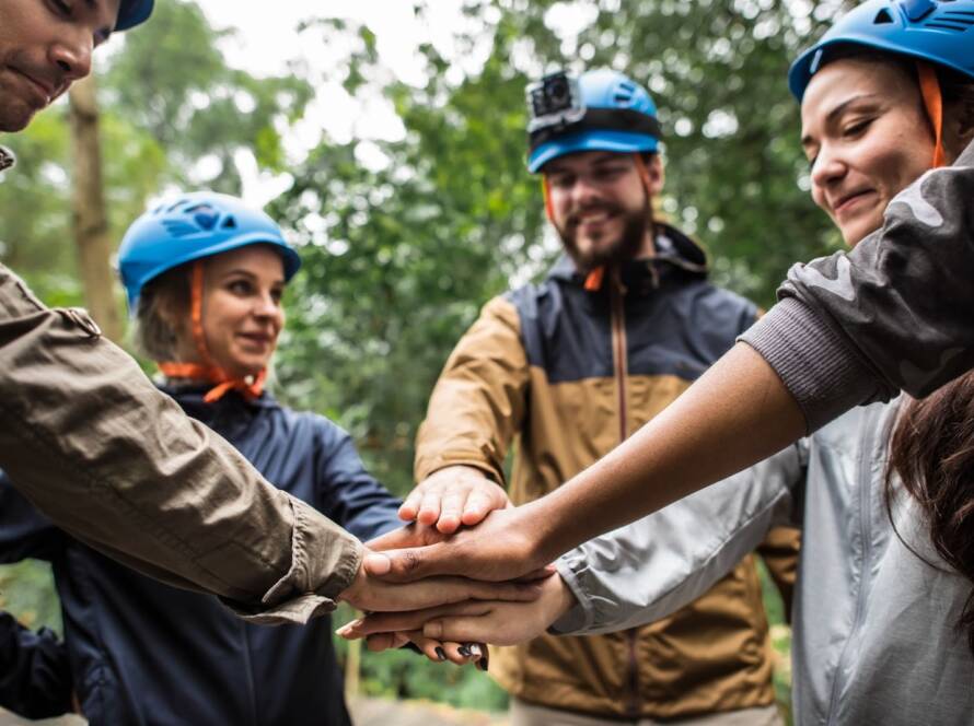 Employees stack their hands together before starting a team-building retreat at the ranch