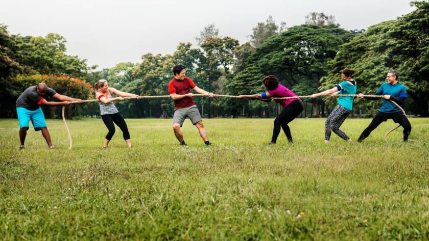 Colleagues participating in an outdoor tug of war during a corporate team building event