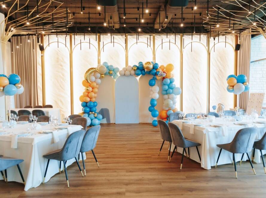 An elegant private event venue featuring a custom balloon arch and coordinated table settings