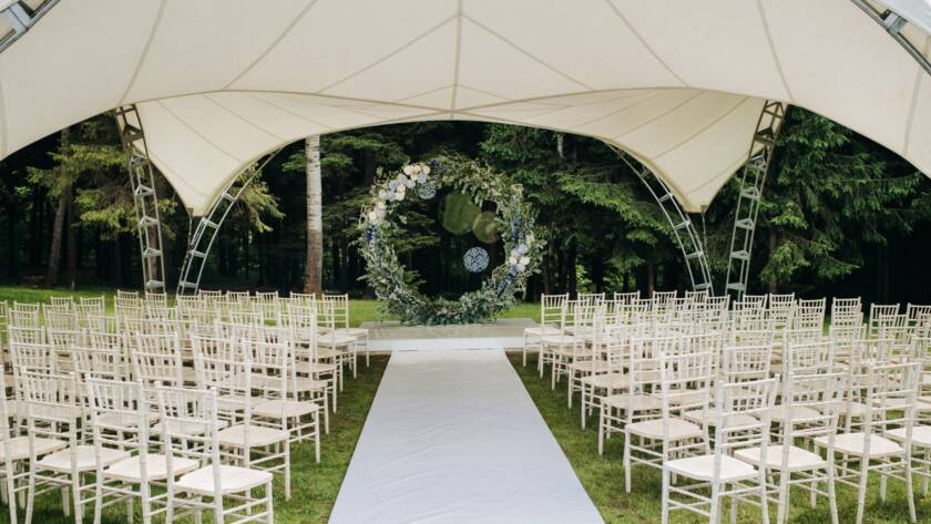 Wedding ceremony on a green lawn with a floral arch and fresh flower decorations at the altar