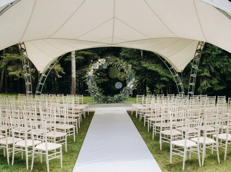 Wedding ceremony on a green lawn with a floral arch and fresh flower decorations at the altar