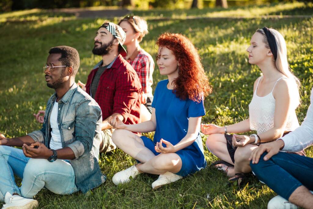 Church retreat participants meditating together outdoors during a peaceful wellness and spiritual reflection session