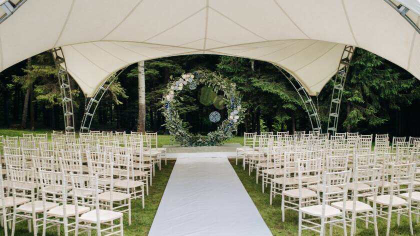Alt-text: Wedding ceremony on a green lawn with a floral arch and fresh flower decorations at the altar