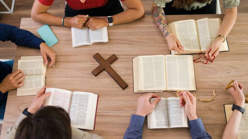 Overhead view of church retreat participants studying religious texts and sharing discussions around a wooden table