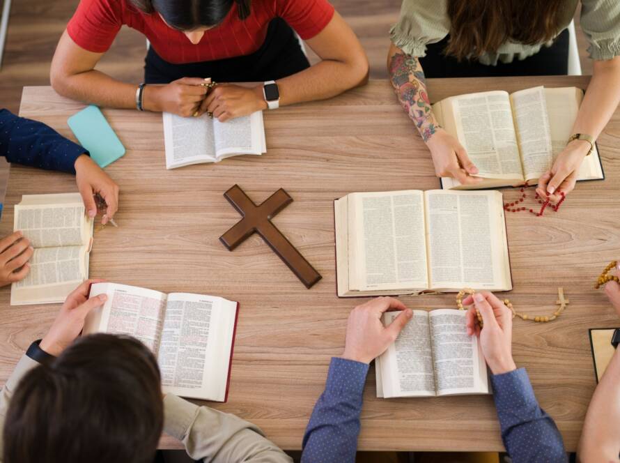 Overhead view of church retreat participants studying religious texts and sharing discussions around a wooden table