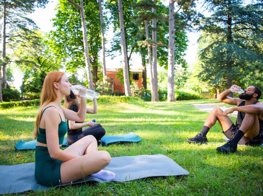 People outdoors on yoga mats on a grass field.