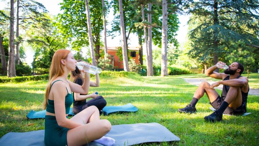 People outdoors on yoga mats on a grass field.